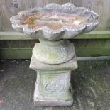 A reconstituted stone bird bath, in the form of a shell, on a pedestal base, 70cm high overall,