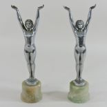 A pair of Art Deco polished metal figures of nude ladies, standing with their arms raised,