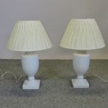 A pair of white glazed pottery table lamps, with pleated shades,