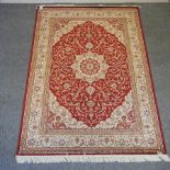 A Keshan style carpet, with a central medallion and foliate designs, on a red ground,