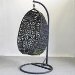 A woven hanging garden chair, on a metal stand,