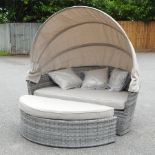 A rattan style garden sofa, with a folding sun canopy,