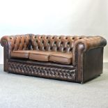 A brown leather upholstered chesterfield sofa,