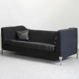 A 1960's style black upholstered sofa, with leather cushions,
