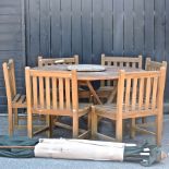 A circular teak garden table, 150cm, together with six teak chairs,