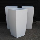 A set of three white garden pots,