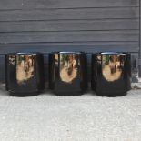 A set of three black circular garden pots,