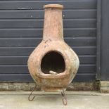 A clay chiminea, on an iron stand,