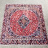 A Persian style woollen carpet, with a central medallion, on a red ground,