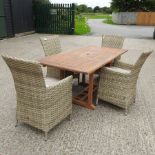 A teak garden table, together with a set of four rattan garden chairs,