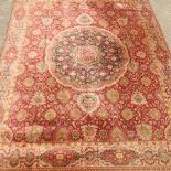 An Axminster style woollen carpet, on a cream ground with a red border,