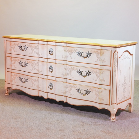A white painted French style chest, with foliate decoration, containing three long drawers,