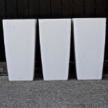 A set of three large white garden pots,