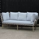 A grey rattan three seater garden sofa, with cushions,