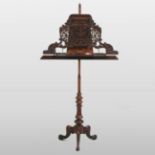 A 19th century carved walnut music stand, having an ornate fret carved adjustable top,