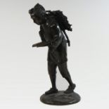 A Chinese bronze figure of a gentleman, in walking pose, carrying a faggot whilst reading a book,