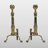 A pair of large antique brass fire dogs, with turned decoration, on claw and ball feet,