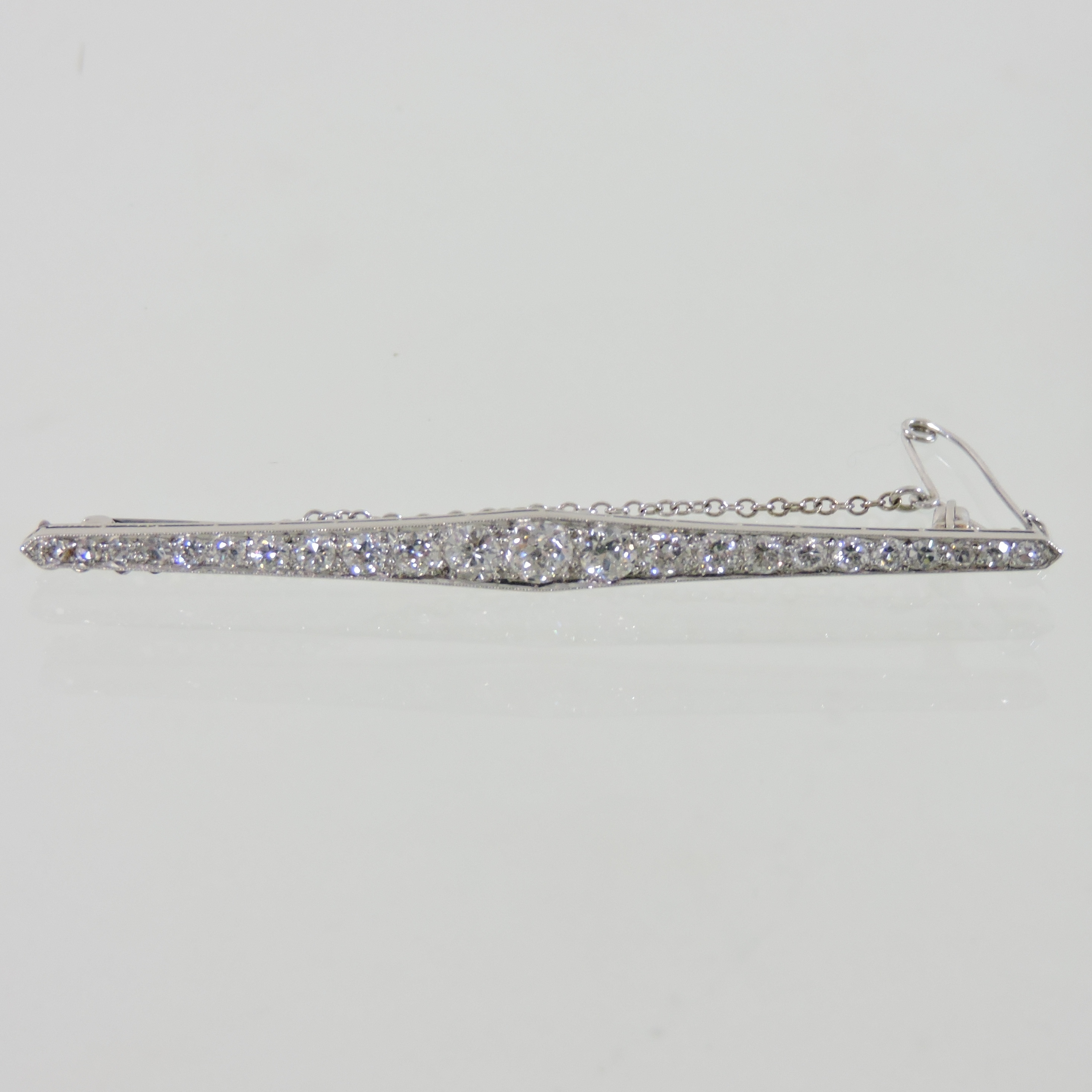 An unmarked twenty three stone diamond bar brooch, set with a single row of graduated stones,