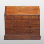 A George III mahogany bureau, containing two short over three long drawers, on a plinth base,