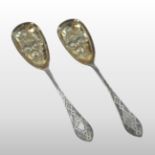 A pair of Victorian silver berry spoons, with engraved decoration and embossed gilt bowls,