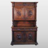 A 19th century continental carved oak cabinet, decorated with masks, flowers and birds,