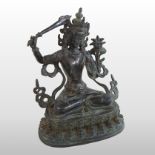 An Eastern bronze figure of a seated deity, holding a sword, with legs crossed,