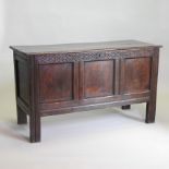 A 17th century oak coffer, of panelled construction, with a hinged lid and carved frieze,