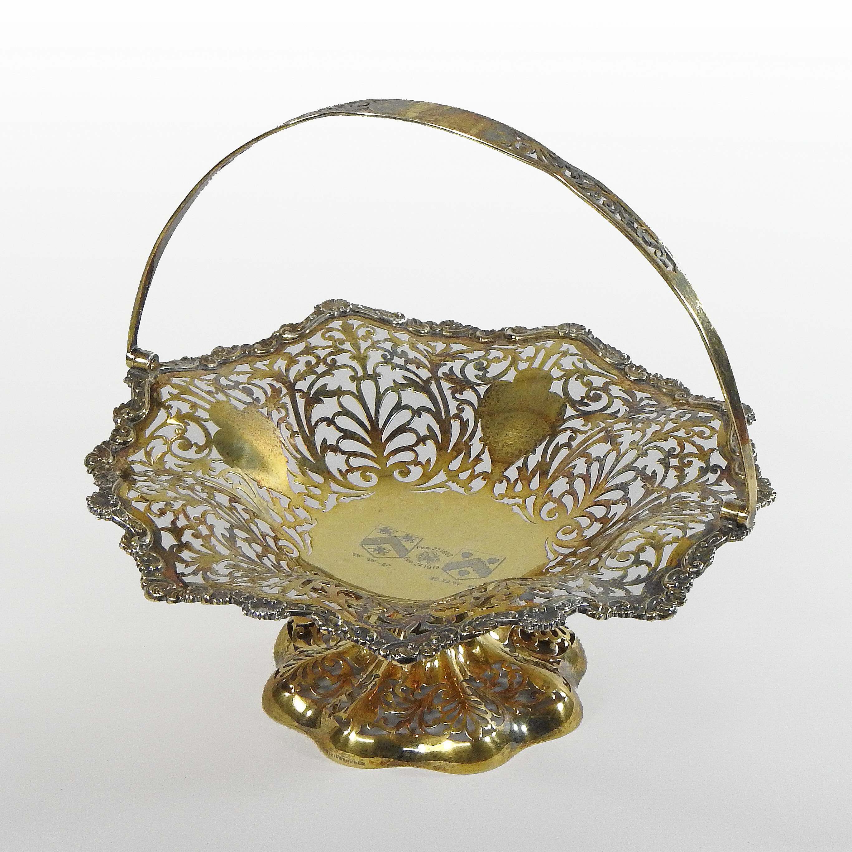 An Edwardian silver gilt cake basket, of pierced scalloped shape, with a swing handle,