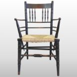 A 19th century ebonised Sussex armchair, with a rush seat, on turned legs,