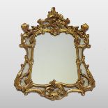 A Rococo style gilt framed wall mirror, with floral and scrolled carving.