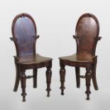 A pair of 19th century oak hall chairs, each with a shield shaped back and solid seat,