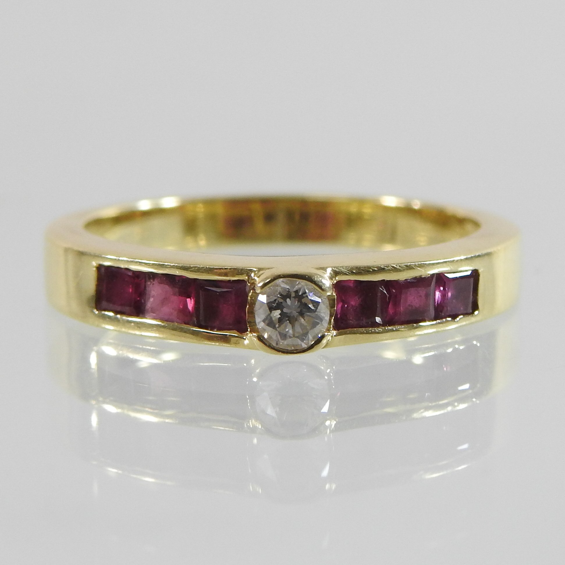 An 18 carat gold diamond ring, with channel set ruby shoulders,