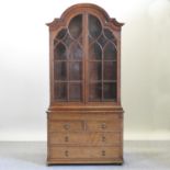 An early 20th century glazed oak bookcase, with an arched top and drawers below,