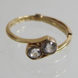 An 18 carat gold two stone gem set ring, of crossover design,