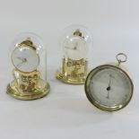 Two anniversary clocks, housed under domes, together with a barometer,