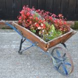 A vintage wooden wheelbarrow, planted with flowers,