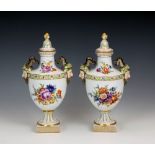 A pair of covered Dresden twin handled vases, c.1900, of urn form, decorated with floral sprays