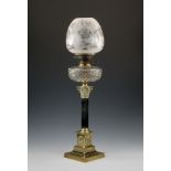 A Victorian brass and cut glass Corinthian column oil lamp, the ebonised column on a brass plinth