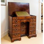 A George III mahogany kneehole desk with lifting top, the unusual lifting moulded edged top