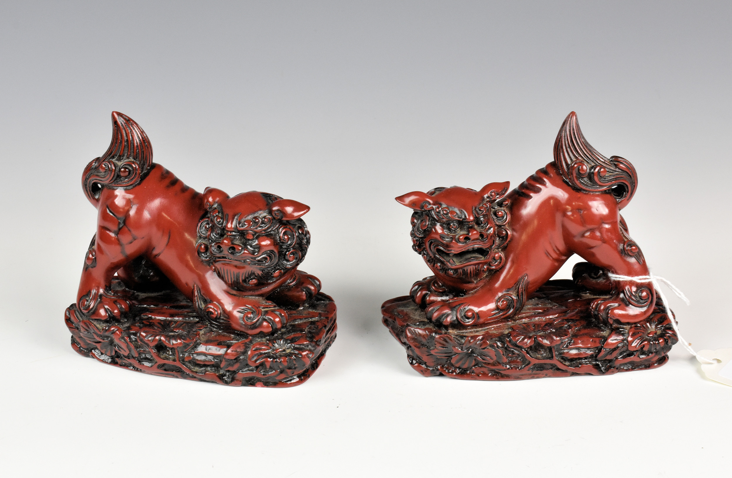 A pair of Chinese cinnabar style resin Foo dogs, 20th century, 5in. (12.7cm.) long. (2)