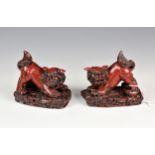 A pair of Chinese cinnabar style resin Foo dogs, 20th century, 5in. (12.7cm.) long. (2)