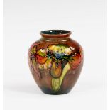 A Moorcroft orchid pattern flambé glaze vase, 1930s, ovoid form, painted on a pale flambé ground