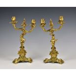 A pair of gilded bronze rococo style two branch candlesticks, 20th century, with foliate branches