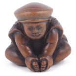 WOOD NETSUKE OF A BOY WEARING DAIKOKU'S CAP, CIRCA 1870 holding his feet joined in front of him,