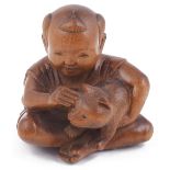 WOOD NETSUKE OF A BOY PETTING A CAT, CIRCA 1870 the cord holes with stained bone rings, signed on