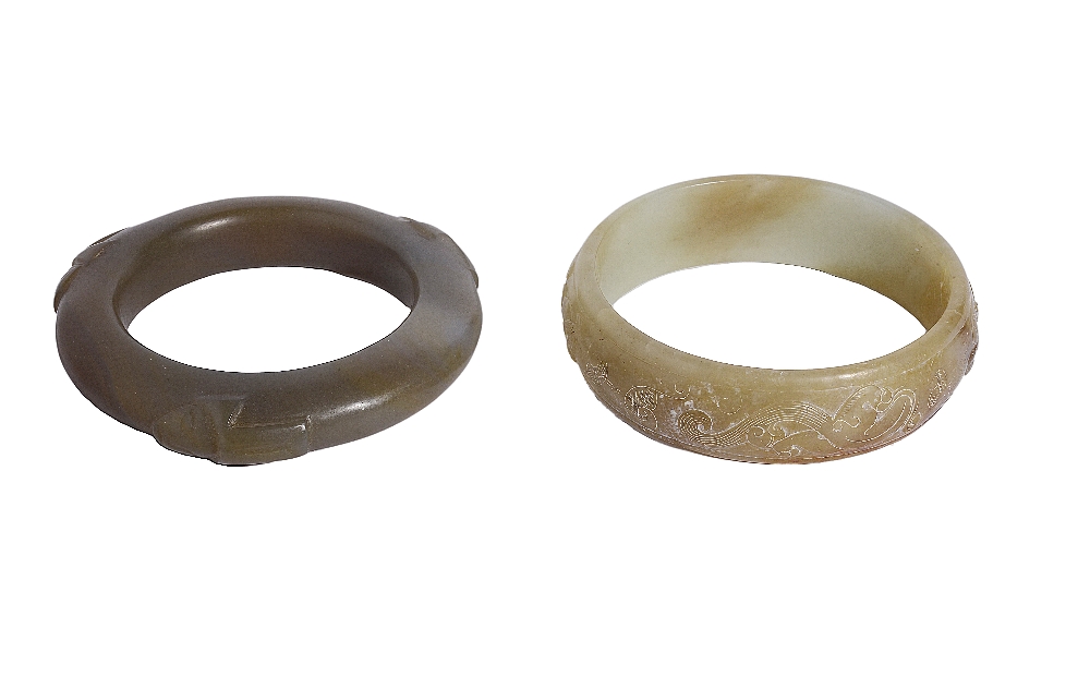 TWO CHINESE ARCHAISTIC JADE BI RINGS one carved in low relief with chilong, the stone of pale