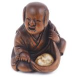 WOOD NETSUKE OF A BOY WITH A MASK IN A FUROSHIKI, CIRCA 1870 the mask of Hyottoko carved from ivory,