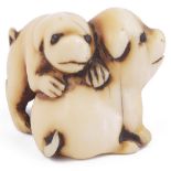 ˜STAINED IVORY NETSUKE OF TWO PUPPIES, CIRCA 1850 their eyes inlaid in dark horn, unsigned 2.9cm
