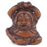 WOOD NETSUKE OF DARUMA, CIRCA 1850 stretching after his years of meditation, unsigned 4.3 cm high