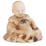 ˜STAINED WALRUS IVORY NETSUKE OF A BOY SEATED WITH A DOG, CIRCA 1870 the dog's eyes inlaid with dark